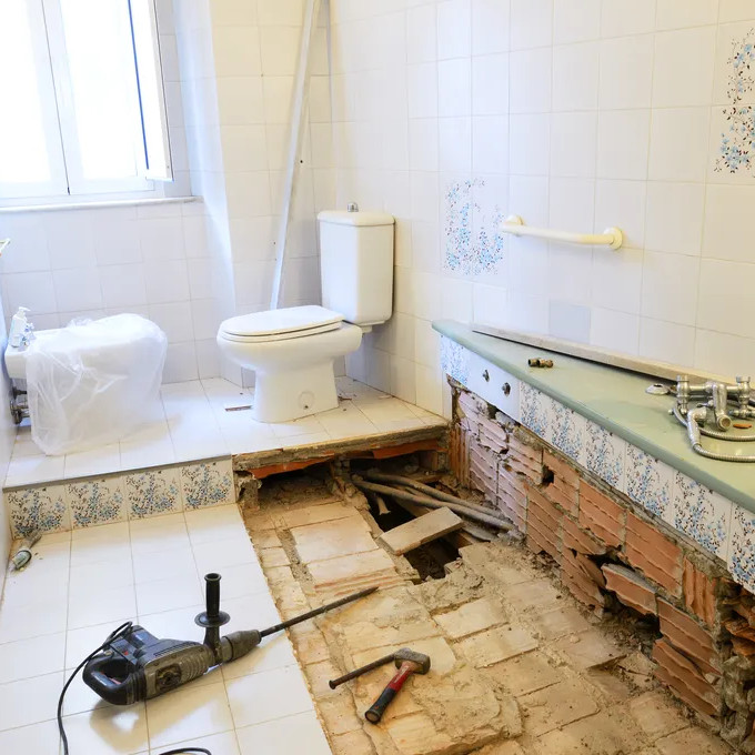 Bathroom under renovation with floor partially removed and tools visible